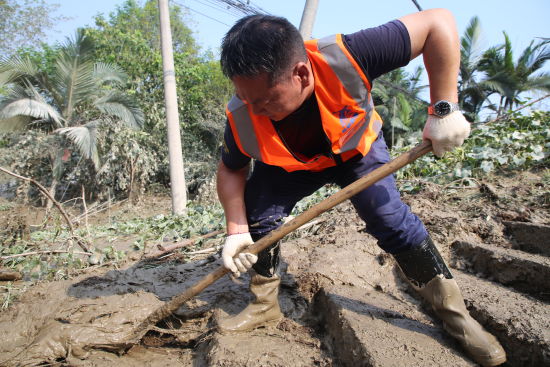 图为志愿者用铁锹铲除淤泥。李俨 摄
