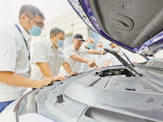 图为 八月十日，吴礼军(左二)正在和同事研究长安新车型的产品竞争力。长安汽车供图