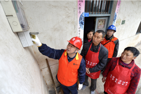 刘军(前左一)为村民讲解漏电保护器使用知识。国网重庆市电力公司供图